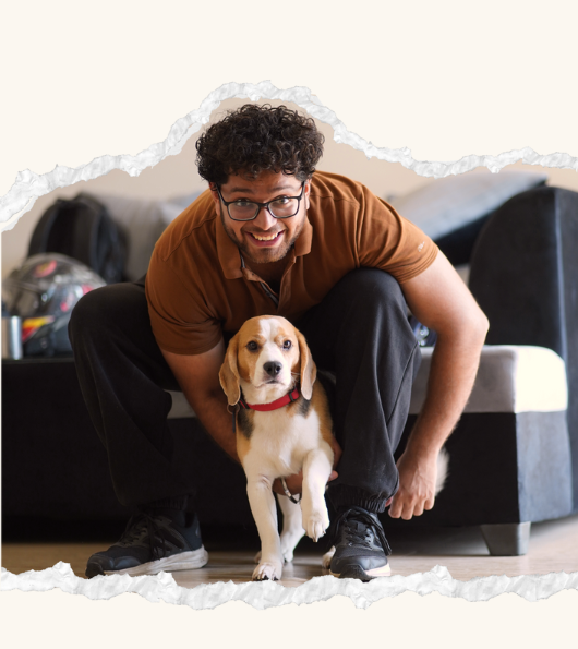 Founder of CanineJoy Gears posing with a beagle dog indoors while sharing the brand story behind durable pet products